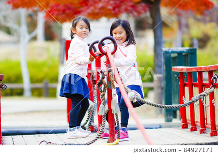 Twin girls playing in the park 84927171