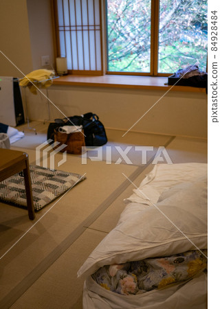 Ryokan room with cluttered luggage and futons 84928484