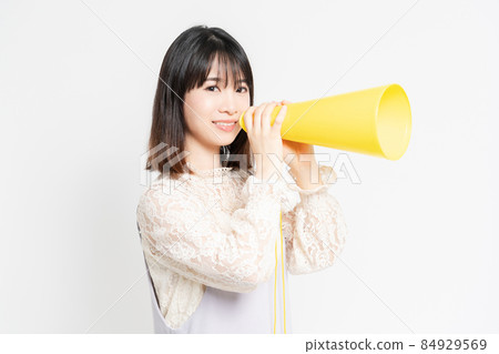 Young woman in a lace blouse standing in front of a white background and cheering Young woman in a lace blouse standing in front of a white background and cheering 84929569