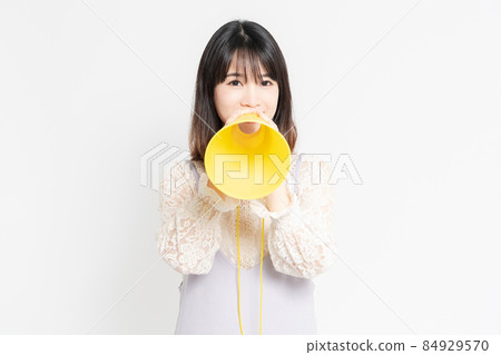 Young woman in a lace blouse standing in front of a white background and cheering Young woman in a lace blouse standing in front of a white background and cheering 84929570