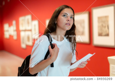 Thoughtful young girl in an art gallery studies works of art 84930269