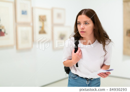 Portrait of focused girl studing works of art in a gallery 84930293
