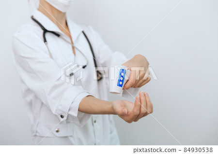 Temperature measurement gun in doctor hands. Close-up shot of doctor wearing protective surgical mask ready to use infrared isometric thermometer gun to check body temperature for virus symptoms. Temperature measurement gun in doctor hands. Close-up shot of doctor wearing protective surgical mask ready to use infrared isometric thermometer gun to check body temperature for virus symptoms. 84930538