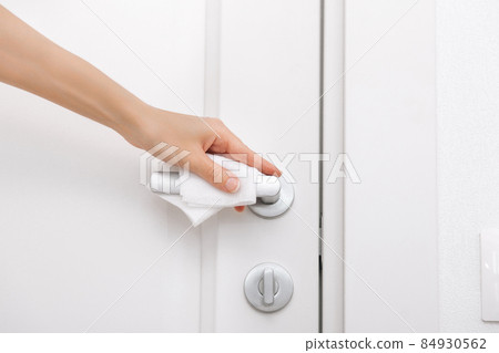 Cleaning door handles with an antiseptic wet wipe and gloves. Sanitize surfaces prevention in hospital and public spaces against corona virus. Woman hand using towel for cleaning home room door link. Cleaning door handles with an antiseptic wet wipe and gloves. Sanitize surfaces prevention in hospital and public spaces against corona virus. Woman hand using towel for cleaning home room door link. 84930562