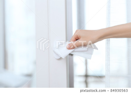 Cleaning door handles with an antiseptic wet wipe and gloves. Sanitize surfaces prevention in hospital and public spaces against corona virus. Woman hand using towel for cleaning home room door link. Cleaning door handles with an antiseptic wet wipe and gloves. Sanitize surfaces prevention in hospital and public spaces against corona virus. Woman hand using towel for cleaning home room door link. 84930563