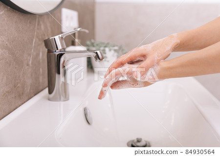 Washing hands under the flowing water tap. Hygiene concept hand detail. Washing hands rubbing with soap for corona virus prevention, hygiene to stop spreading corona virus in or public wash room. Washing hands under the flowing water tap. Hygiene concept hand detail. Washing hands rubbing with soap for corona virus prevention, hygiene to stop spreading corona virus in or public wash room. 84930564