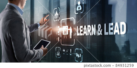 Learn and Lead. Businessman presses hand on the virtual screen inscription 84931259