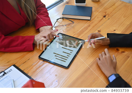 Two business people analyzing financial graph on digital tablet together. Two business people analyzing financial graph on digital tablet together. 84933739
