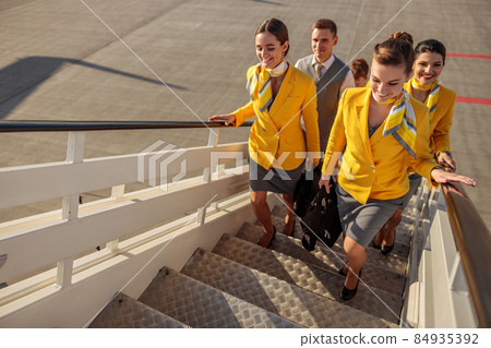 Cheerful airline workers walking up airplane stairs 84935392