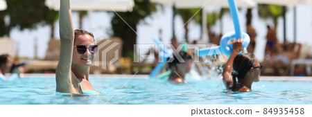 Young women during water aerobics classes in hotel pool closeup Young women during water aerobics classes in hotel pool closeup 84935458