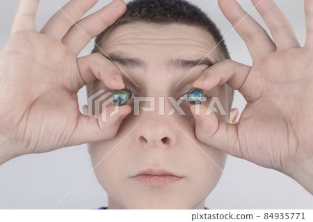 Conceptual shot of an eye crystalline lens replacement. Ophthalmic surgery. Return of sight. Removal of cataracts. Surgical intervention in the eyeball. Doctor holds the implant near the patient 84935771