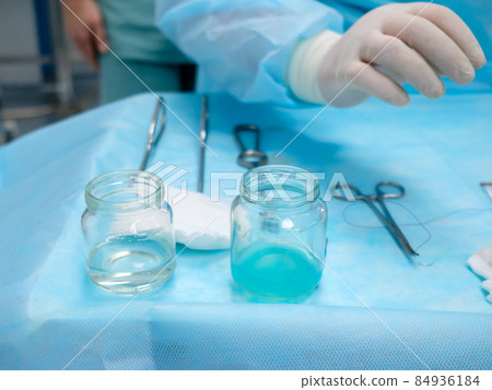 Sterile surgical instruments and glass containers with solutions on the table during a surgical operation. Sterile surgical instruments and glass containers with solutions on the table during a surgical operation. 84936184