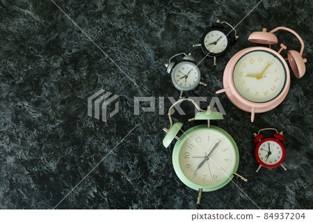 Multicolor alarm clocks on black smokey table 84937204