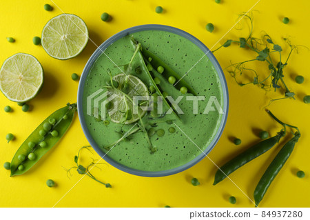 Plate of pea soup and ingredients on yellow background 84937280
