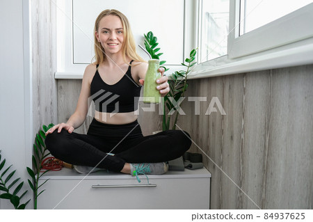 Young millenial blond woman drinking vegan smoothie drink detox. Woman doing yoga exercises at home. Clean eating, weight loss, healthy dieting food concept. Stay healthy 84937625