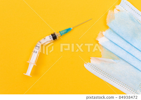 Broken Medical Syringe and Torn Medical Face Mask 84938472