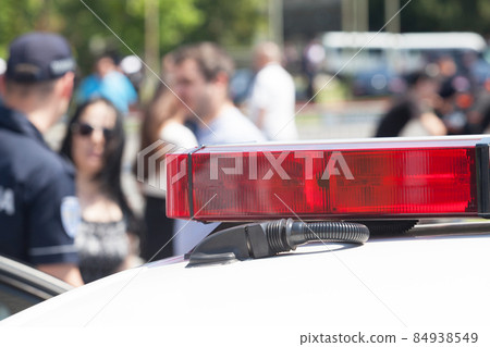 Police car flashing lights in focus, blurred people in background Police car flashing lights in focus, blurred people in background 84938549