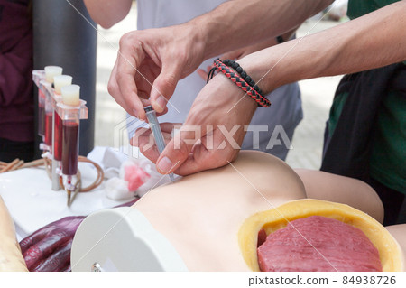 Practicing to give an intramuscular injection 84938726