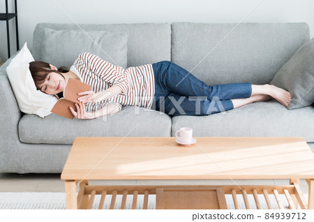 一個女人躺在沙發上看書 一個女人躺在沙發上看書 84939712