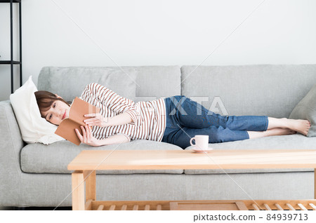 A woman reading while lying on the sofa 84939713