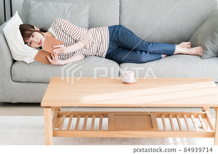 A woman reading while lying on the sofa 84939714