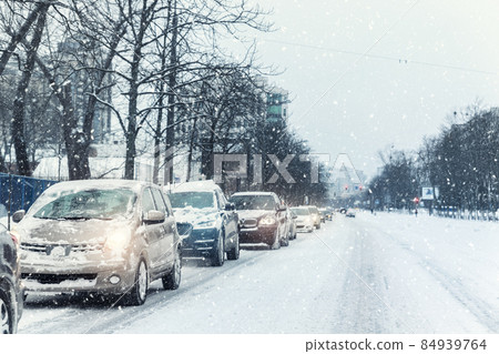 Scenic view traffic city jam at crossroad dirt snow covered slippery road drive slow moving cars stuck. Snowfall danger blizzard bad winter weather. Urban cold foggy day snowstrom town background 84939764