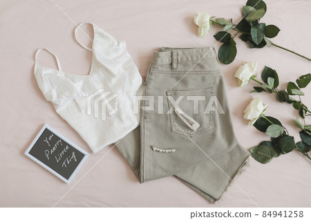 Women jeans, sandals, lingerie and flowers top view. Women's stylish spring summer outfit. Trendy clothes. Flat lay. 84941258