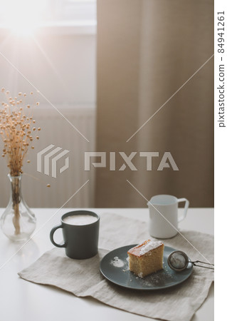 breakfast with a piece of fresh homemade cake, pitcher and cup of coffee on a table breakfast with a piece of fresh homemade cake, pitcher and cup of coffee on a table 84941261