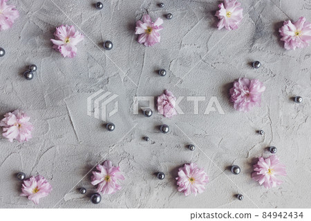 Pink sakura flowers and pearls on gray background 84942434