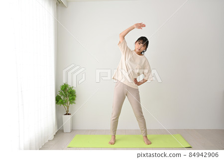 Young woman doing stretching exercises on an indoor mat 84942906