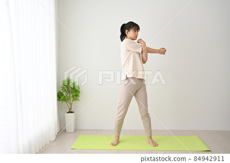 Young woman doing stretching exercises on an indoor mat 84942911