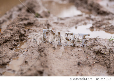 the word dirt composed of silver metal letters on wet clay surface the word dirt composed of silver metal letters on wet clay surface 84943098
