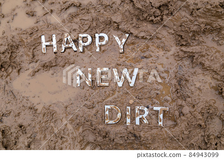 the words happy new dirt laid with silver metal letters on wet mud surface 84943099