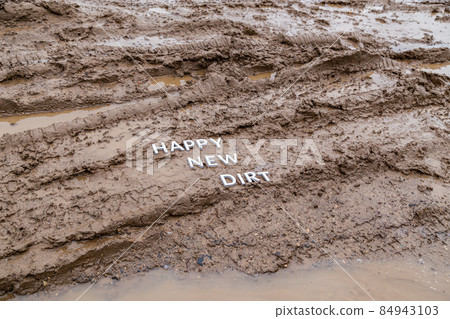 the words happy new dirt laid with silver metal letters on wet mud surface 84943103