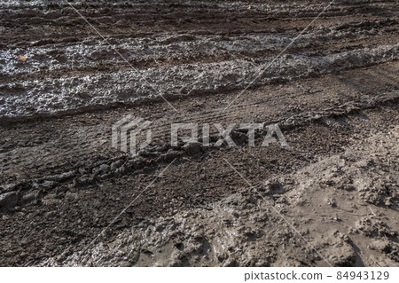 close-up full frame view of wet muddy dirt road at evening sun light close-up full frame view of wet muddy dirt road at evening sun light 84943129