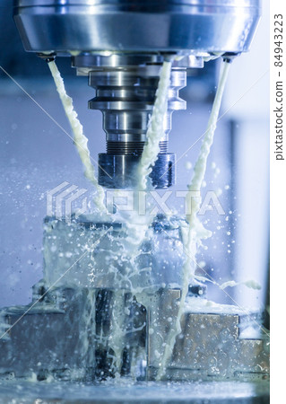 Vertical photo of industrial wet milling process in 5-axis cnc machine with coolant flow under pressure and freezed splashes 84943223