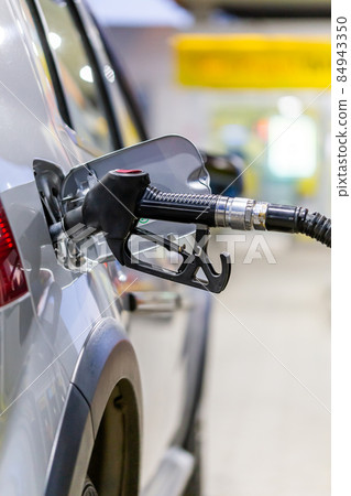 silver mettalic color car refueling on public gas station - close-up with selective focus and blurry background 84943350