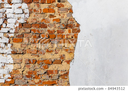old bad brick wall with leftovers of white peeled thick plaster old bad brick wall with leftovers of white peeled thick plaster 84943512