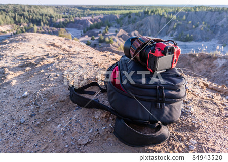 professional camera and photo backpack on top of the hill at summer daytime 84943520