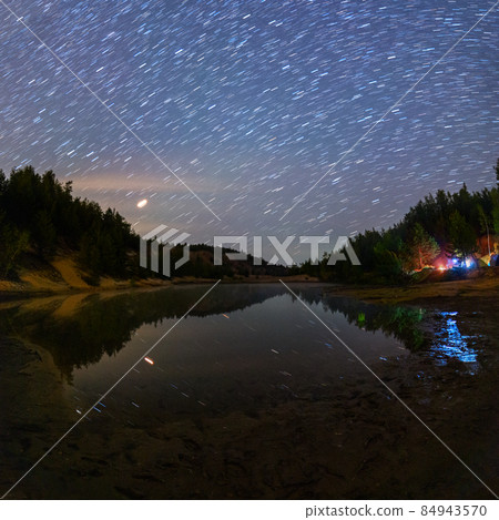 small lake under stars at night with short rails and camping at summer 84943570