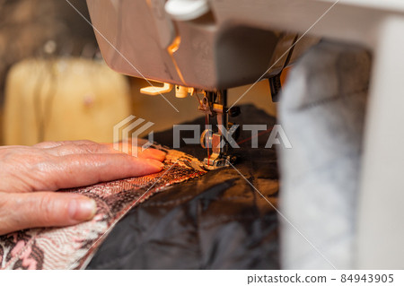 a close-up view of sewing process, hand of old woman using sewing machine, selective focus technique a close-up view of sewing process, hand of old woman using sewing machine, selective focus technique 84943905