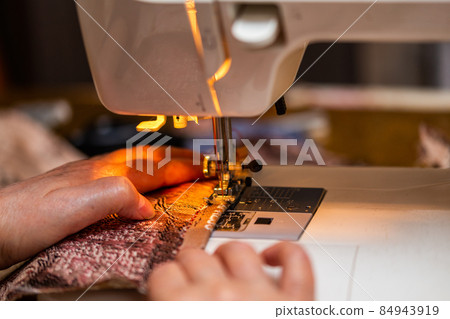a close-up view of sewing process, hand of old woman using sewing machine, selective focus technique a close-up view of sewing process, hand of old woman using sewing machine, selective focus technique 84943919