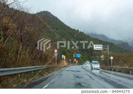 Highway scenery on a rainy day seen from the passenger seat 84944273