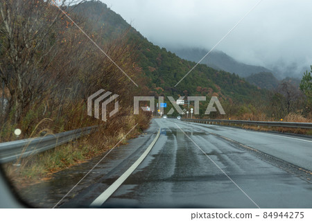 Highway scenery on a rainy day seen from the passenger seat 84944275