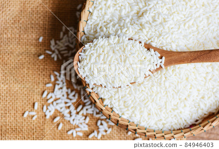 Jasmine white rice on wooden spoon on the basket in the the sack, harvest rice and food grains cooking concept Jasmine white rice on wooden spoon on the basket in the the sack, harvest rice and food grains cooking concept 84946403