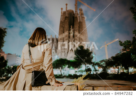 Woman sitting and watching to Gaudi's Masterpiece - Sagrada Familia Basilica at night .Impressive 84947282