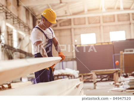 Male builder carrying wooden plank at construction site Male builder carrying wooden plank at construction site 84947520