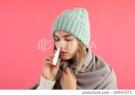 Young woman using nasal spray on pink background, runny nose concept 84947872