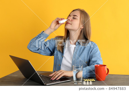 Woman with nasal drops sitting on workplace, runny nose concept 84947883