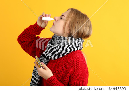 Young woman with nasal drops on yellow background, runny nose concept 84947893